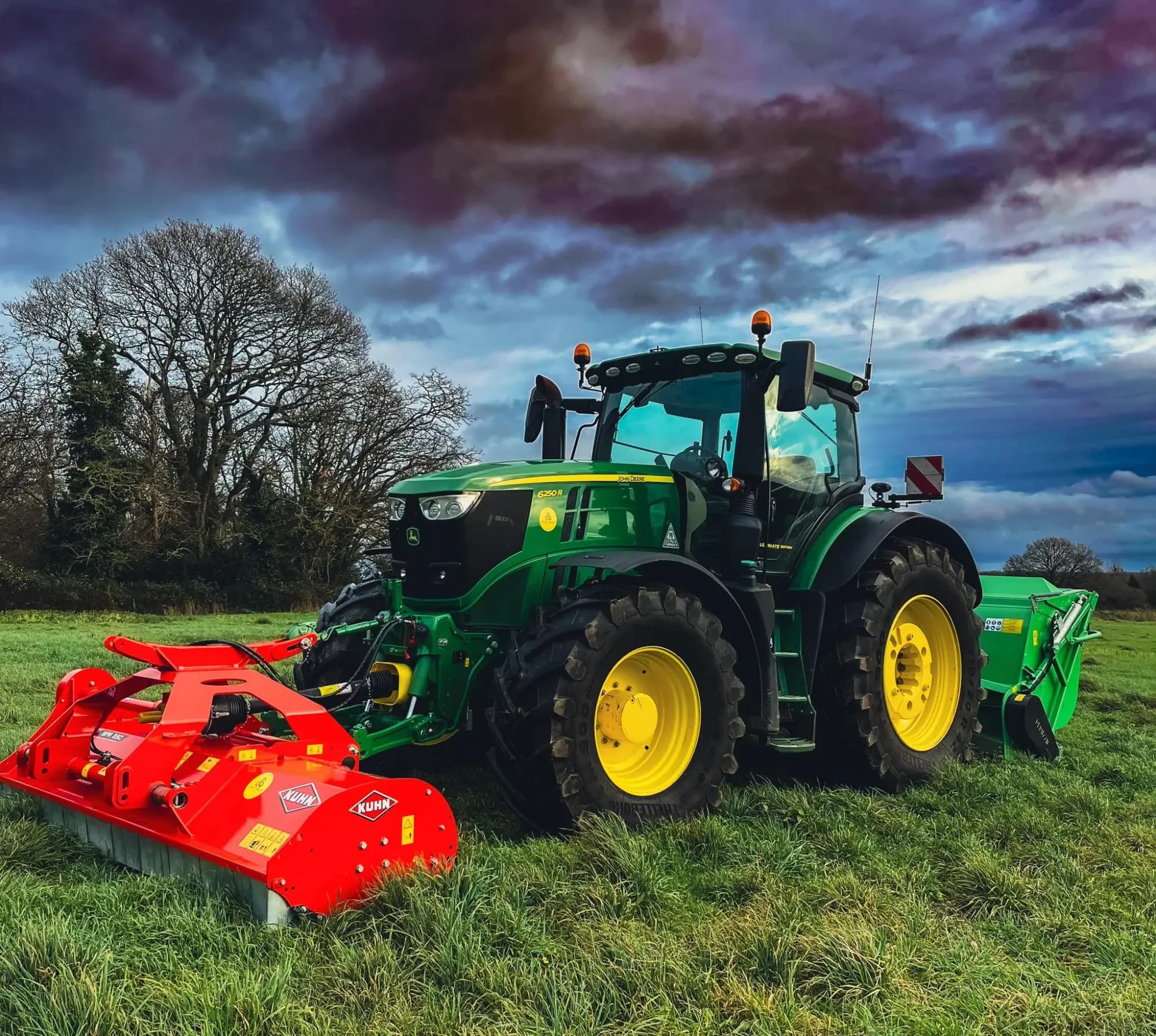 John Deere 6250R with flail mower and collector in a grass field under an autumn sky